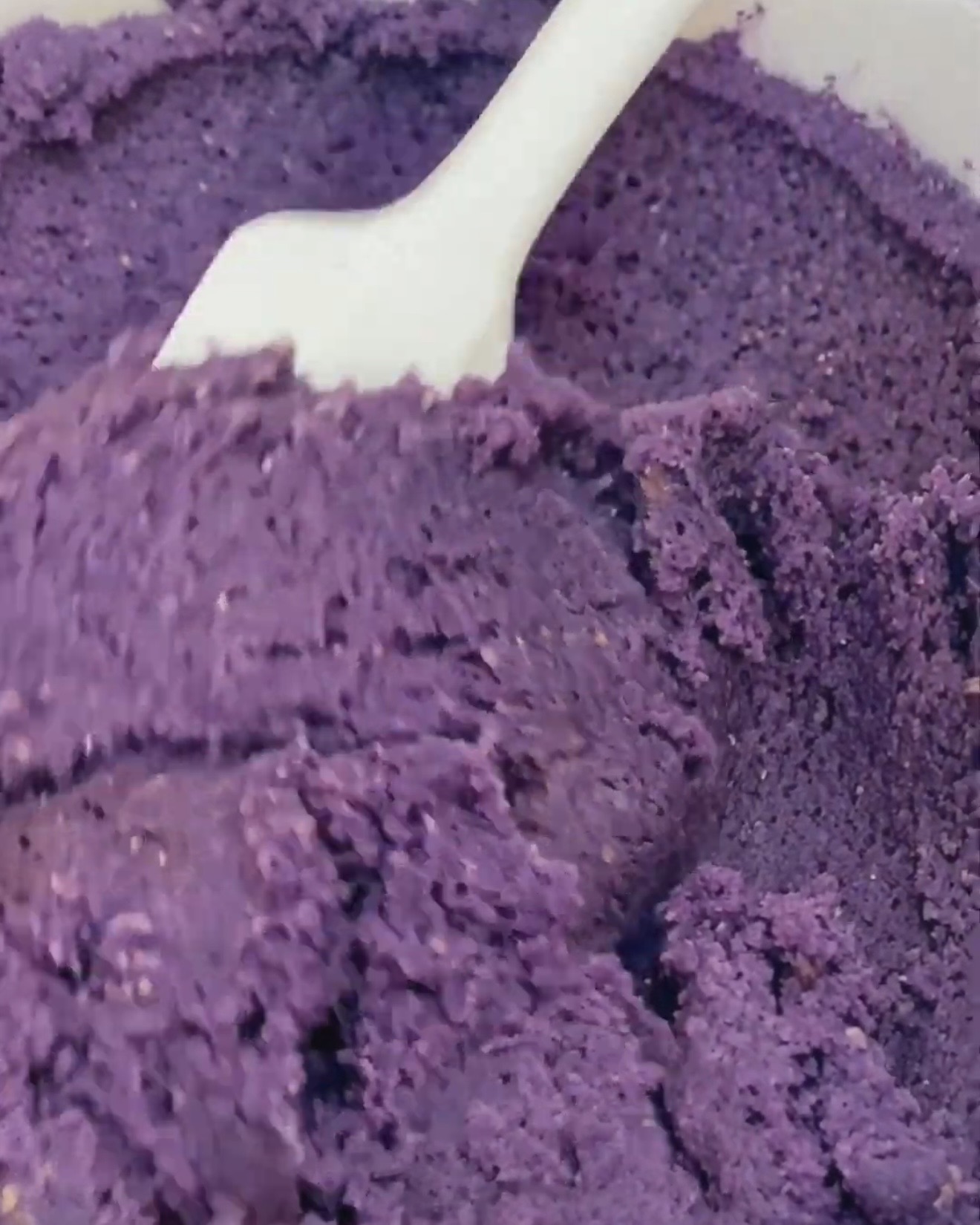 Dyb lilla ube cookie dej foldes med en hvid spatel efter tilsætning af UBE NOLIA ubepulver