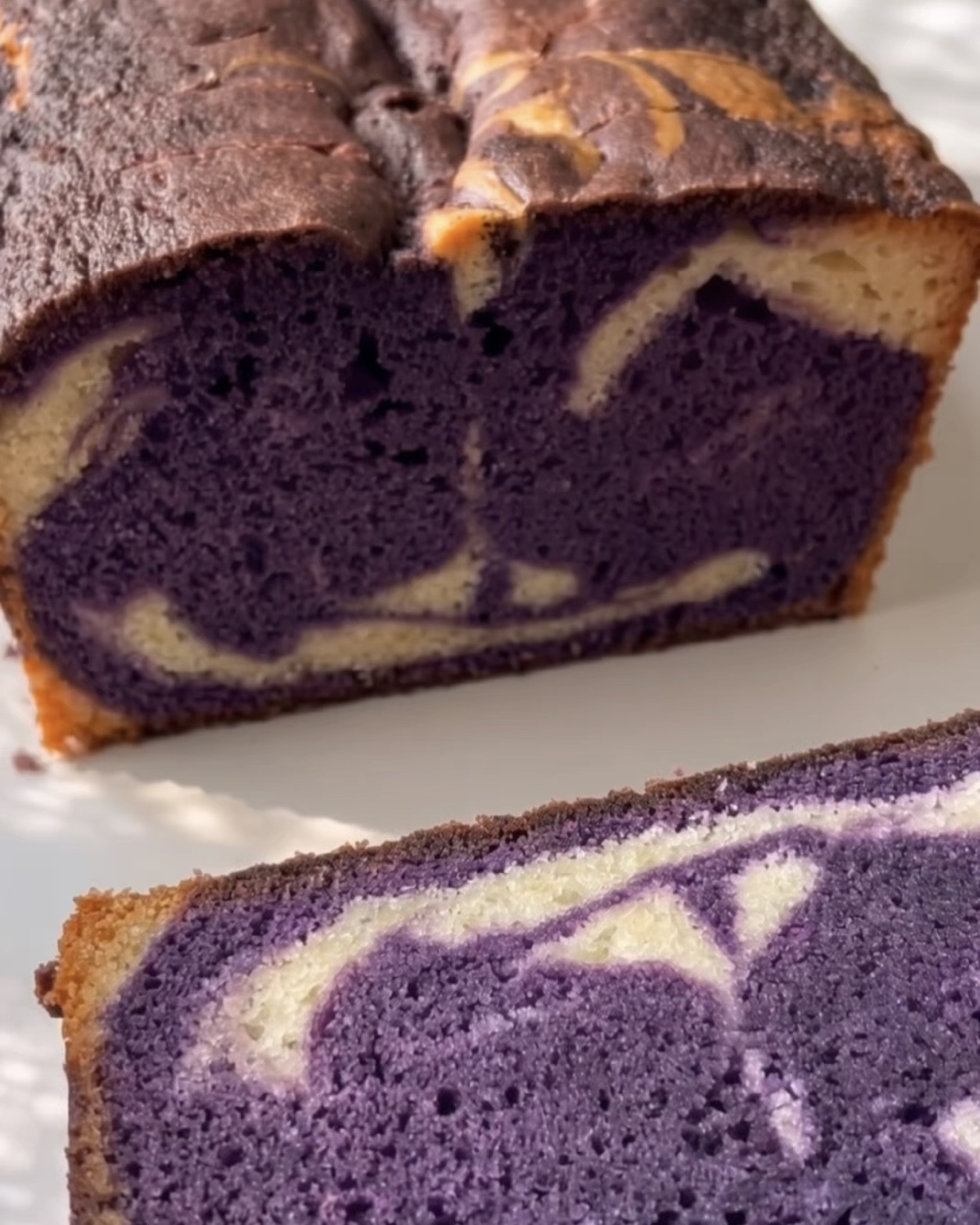 Bagte ube marble pound cake skåret op, der viser den lilla og vaniljefarvede hvirvel, lavet med Ube Nolia ubepulver