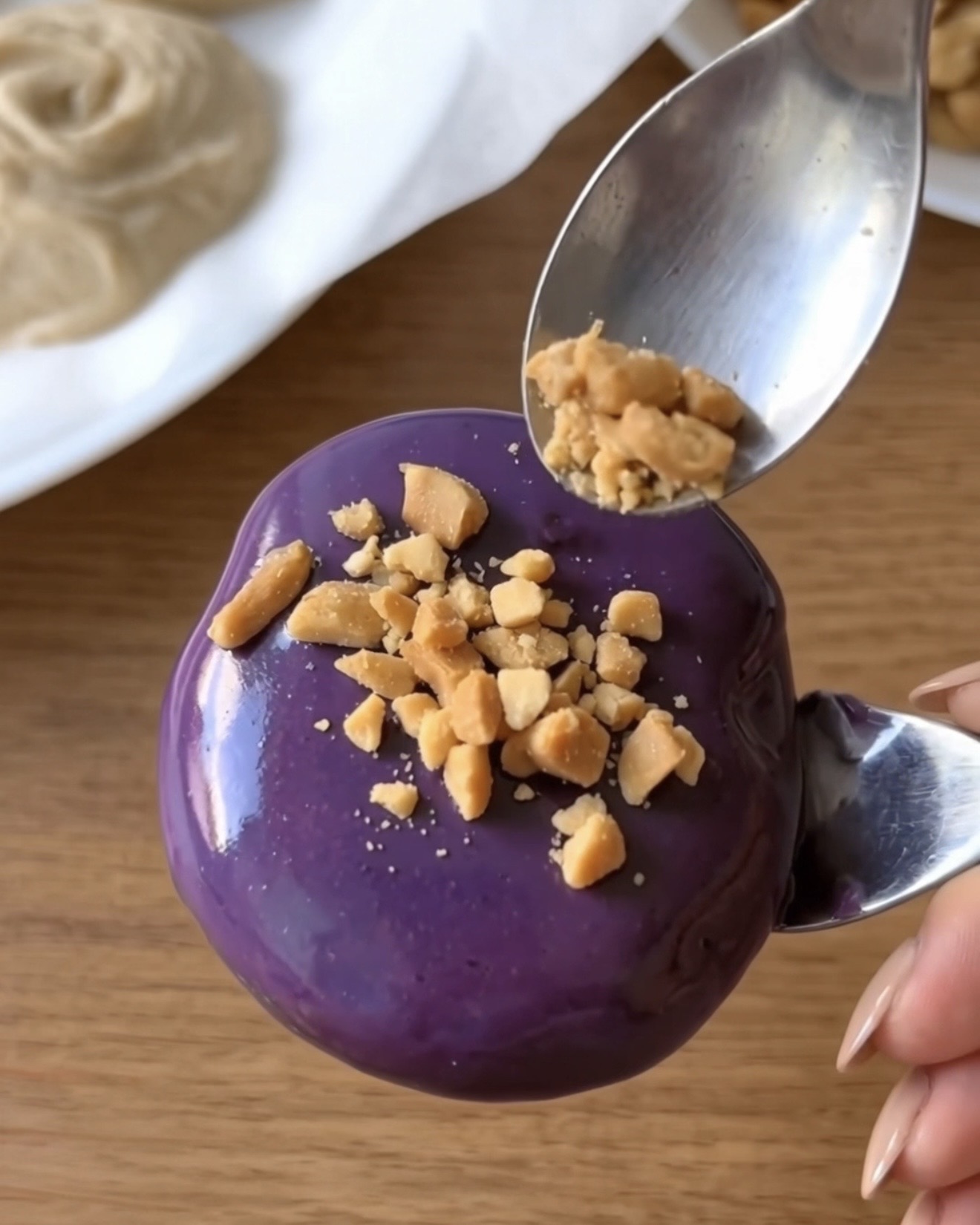 Knuste ristede jordnødder drysset på en lilla ube hvid chokoladeovertrukket Ube Nolia frossen yoghurtbid