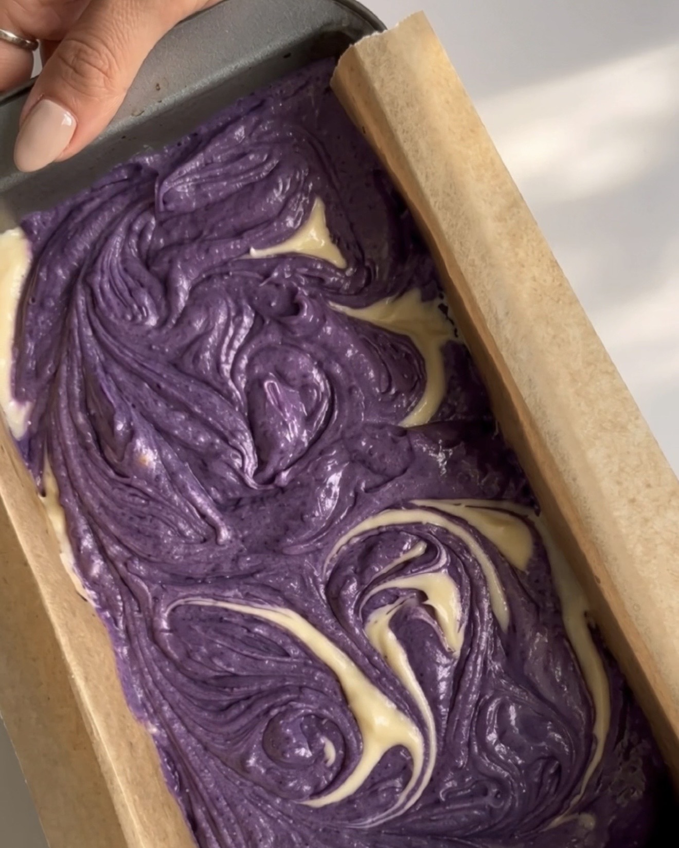 Lilla og vaniljefarvet dej hvirvlet sammen i et marmormønster i brødformen til Ube Nolia ube marble pound cake