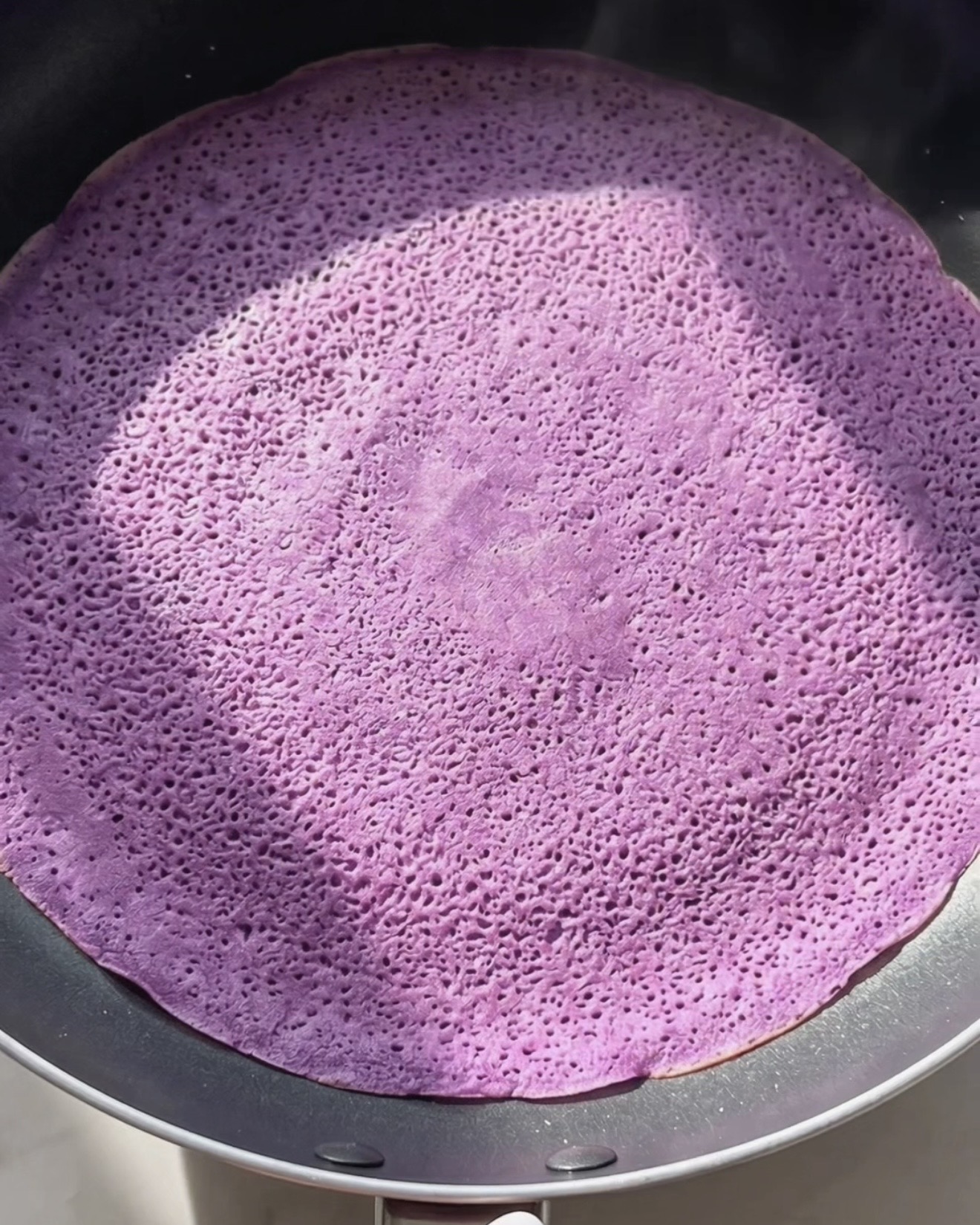 Stegning af tynd lilla ube dadar gulung pandekage på en nonstick-pande