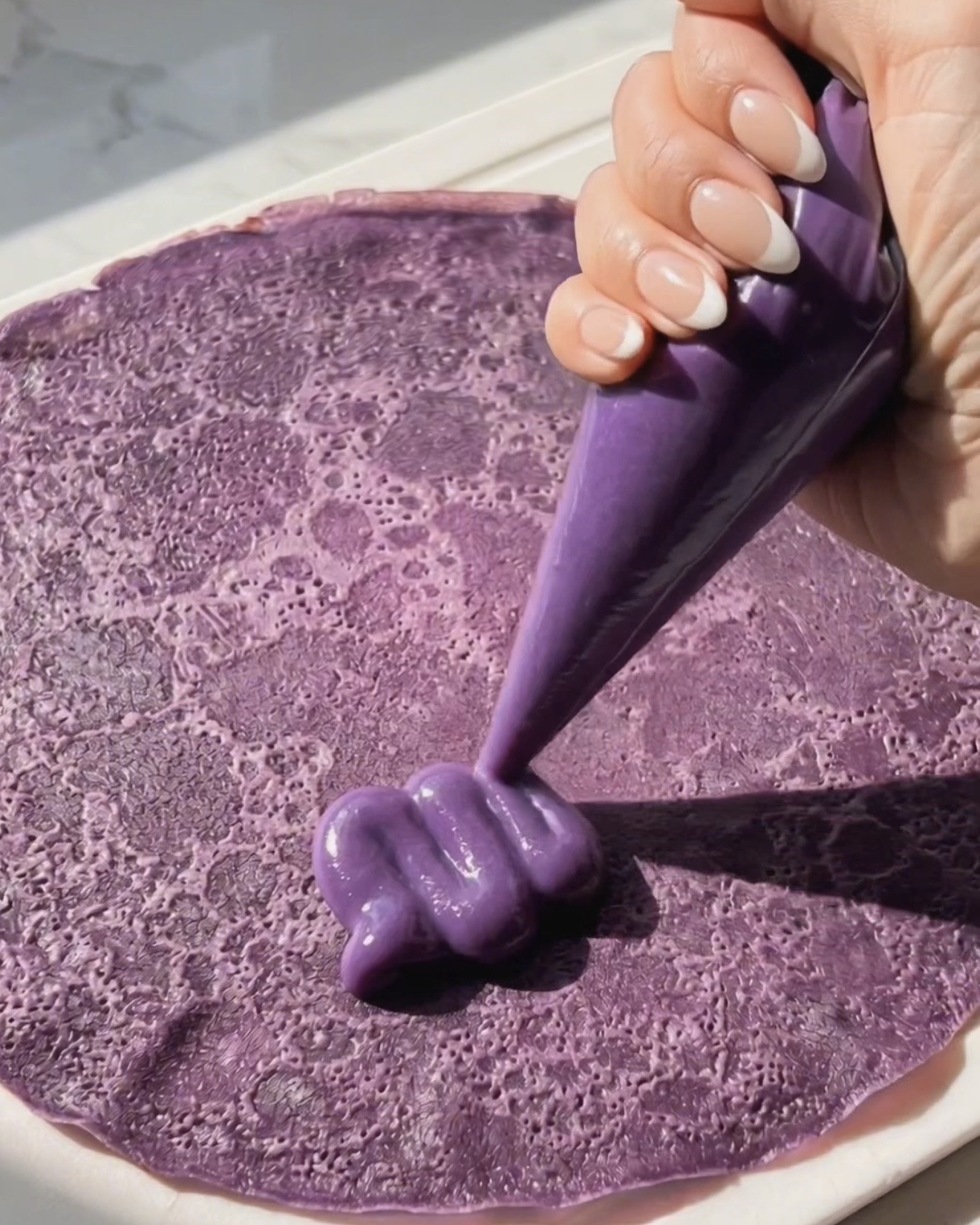 Sprøjtning af ube halaya fyld på en lilla ube pandekage til dadar gulung samling