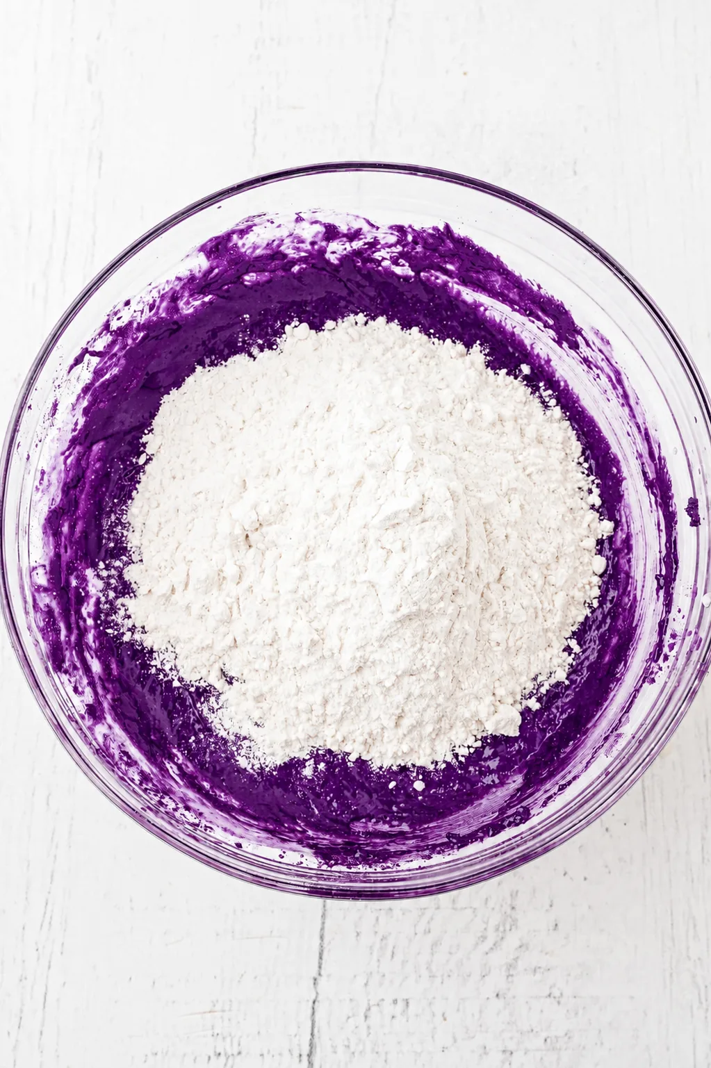 Mel tilsat oven på den dyblilla ube hvid chokolade brownie dej i en glasskål, klar til at folde med Ube Nolia powder