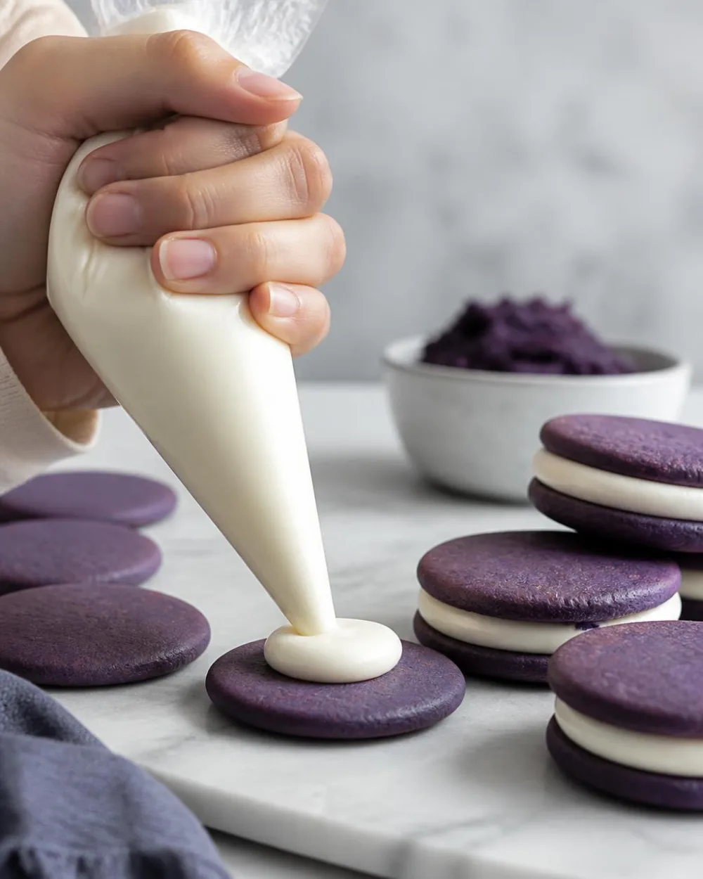 Fyldning af ube Oreo cookies – sprøjter hvid chokolade ganache på lilla ube kiks | Ube Nolia