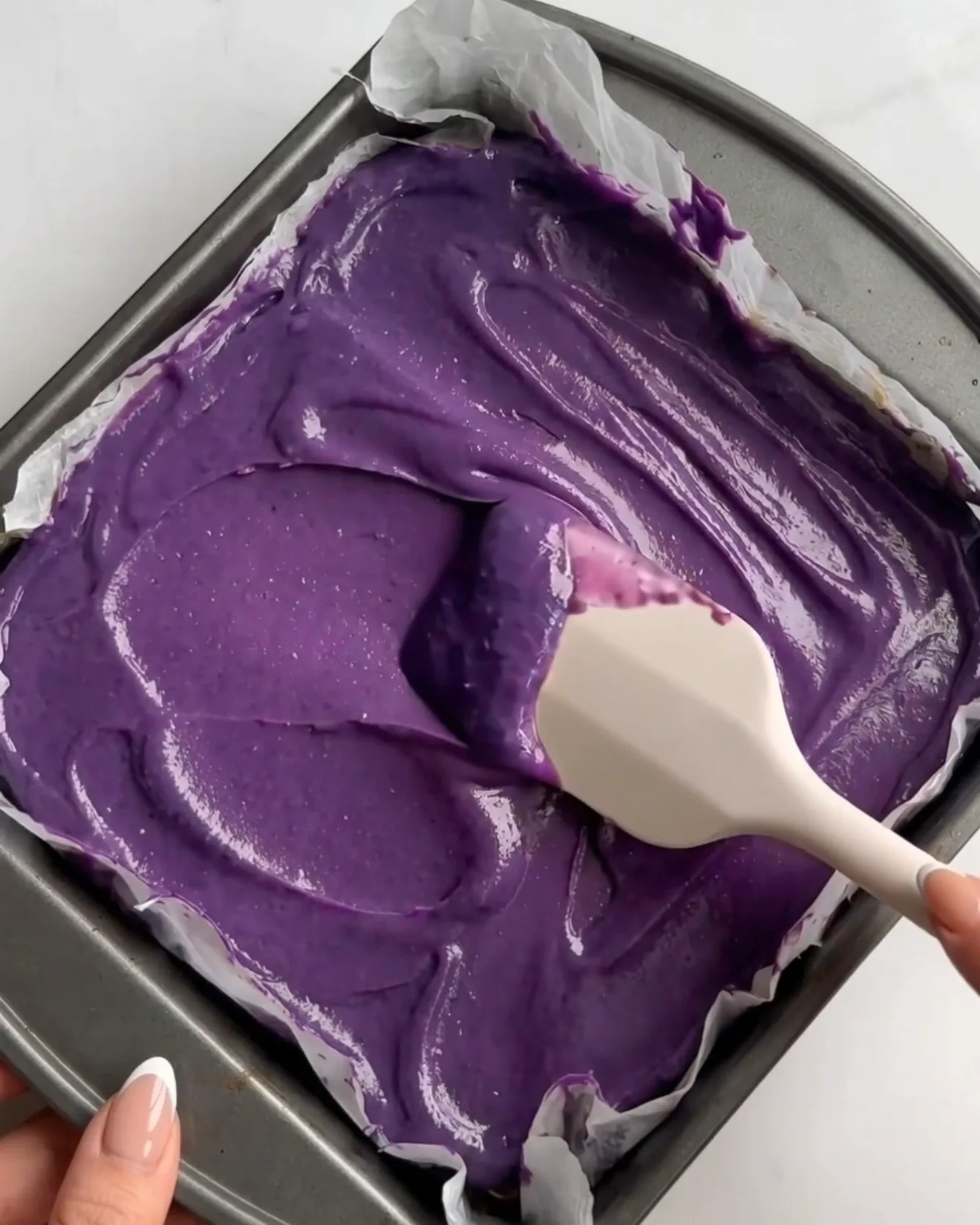 Levende lilla ube hvid chokolade ganache spredes over pistacie kataifi laget til Ube Dubai chokolade brownie bars af Ube Nolia