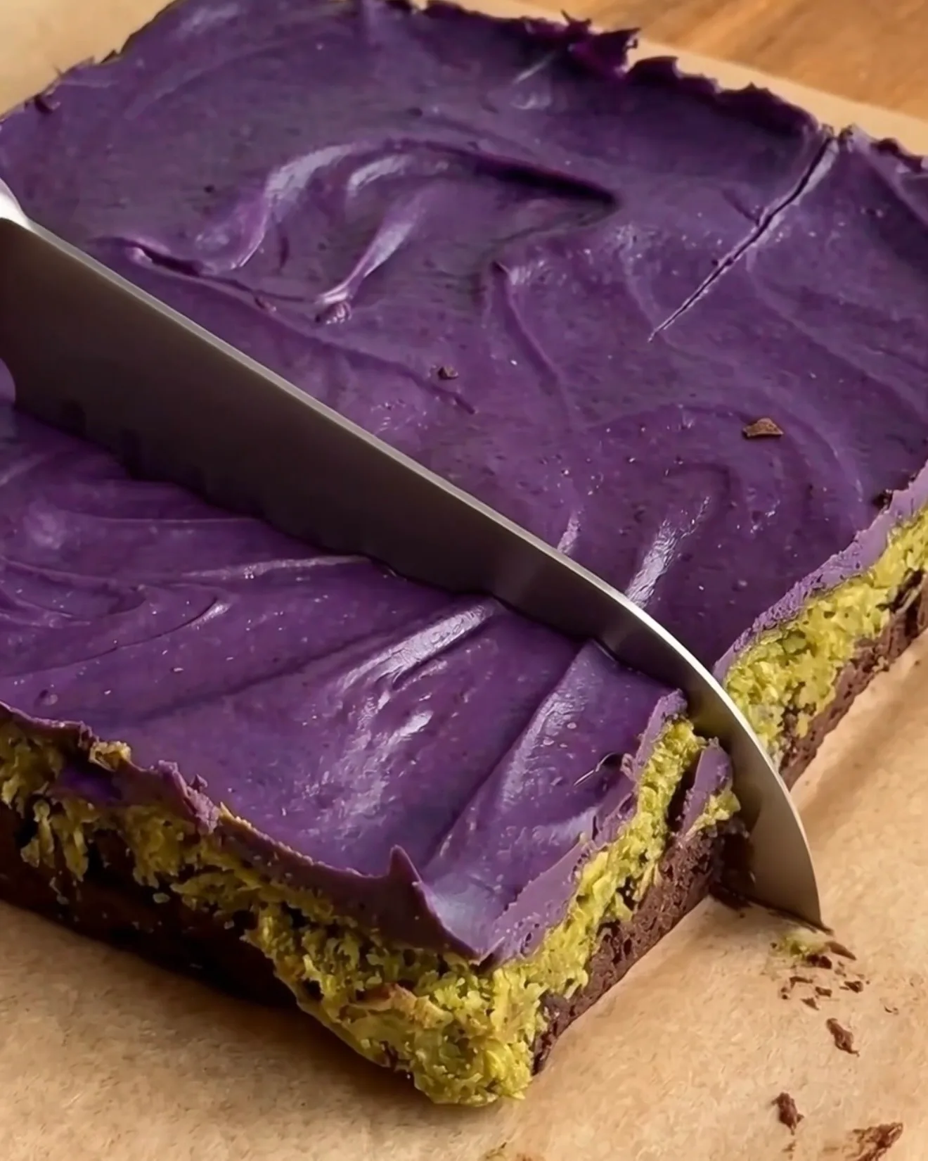 Skæring af afkølede Ube Dubai chokolade brownie bars, der viser brownie-, pistacie kataifi- og ube hvid chokolade-lagene af Ube Nolia